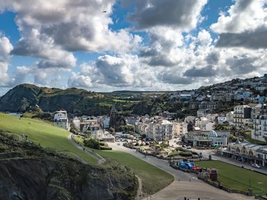 A coastal town with buildings and green hills under a cloudy sky at Ilfracombe