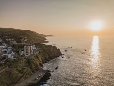 A coastal town with buildings on cliffs overlooking the sea at sunset at Hollycombe in Ilfracombe