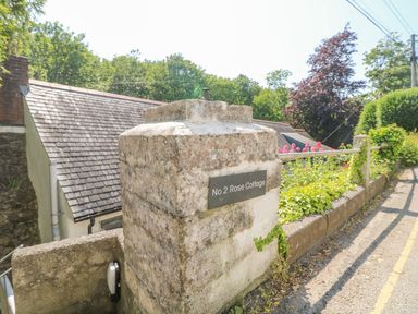 A stone pillar with a sign that reads No 2 Rose Cottage next to a garden and a road at 2 Rose Cottage in St Agnes