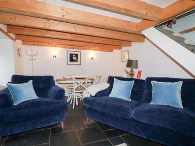 A living room with blue sofas and light wood ceiling beams at 2 Rose Cottage in St Agnes