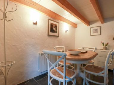 A dining room with wooden table and four chairs with wooden beams on ceiling at 2 Rose Cottage in St Agnes