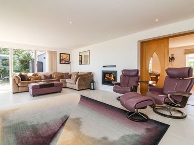 A living room with a brown sectional sofa a purple ottoman two purple recliner chairs a fireplace and sliding glass doors at Buddicombe House in Combe Martin
