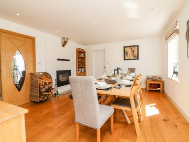 A dining room with a set dining table chairs fireplace and wood storage at Buddicombe House in Combe Martin