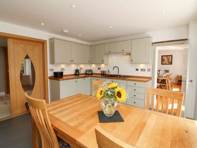 A kitchen with wooden dining table and chairs and cabinets with appliances at Buddicombe House in Combe Martin