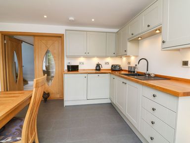 A kitchen with wooden countertops white cabinets and wooden double doors at Buddicombe House in Combe Martin