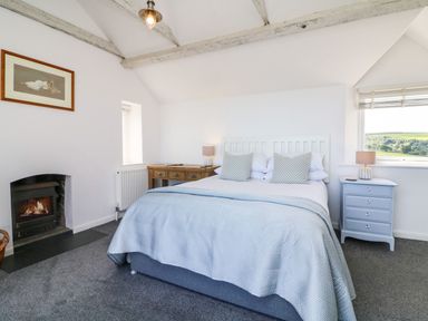 A bedroom with a bed a fireplace a wooden desk and a window with a view at Buddicombe House in Combe Martin