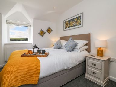 A bedroom with a bed and yellow blanket with breakfast tray on bed at Buddicombe House in Combe Martin