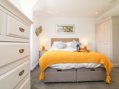 A bedroom with a bed yellow throw and bedside tables at Buddicombe House Combe Martin