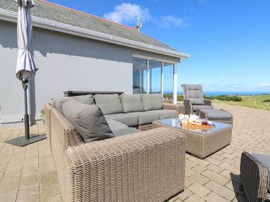 An outdoor patio with wicker furniture and a table with tea set at Buddicombe House in Combe Martin