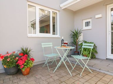 A patio with a small table and two chairs with a bottle of wine and glasses and potted plants at Buddicombe House in Combe Martin