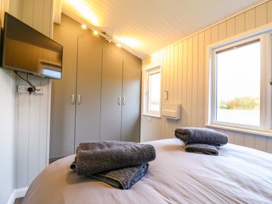 A bedroom with a bed with folded towels a wall-mounted television and a wardrobe at Cuckoo in Ramsey Huntingdon
