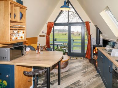 A kitchen and dining area with a wood stove and glass doors leading to a patio at Sunflower Lodge Near Misterton