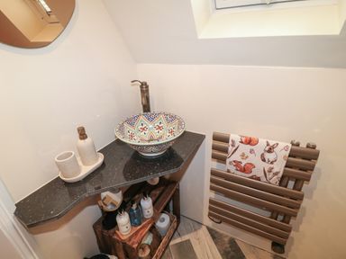 A bathroom corner with a decorative sink faucet soap dispenser towel rack and wooden shelf at Sunflower Lodge Near Misterton