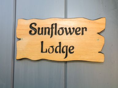 A wooden sign with Sunflower Lodge text mounted on a gray door at Sunflower Lodge Near Misterton