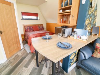 A small room with a bed dining table microwave and sofa at Sunflower Lodge Near Misterton