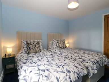 A bedroom with two single beds with floral bedding and two bedside tables with lamps at Court House Cottage in Gatcombe near Blakeney