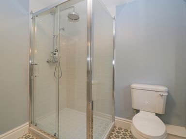 A bathroom with a glass shower enclosure and a white toilet at Court House Cottage in Gatcombe near Blakeney