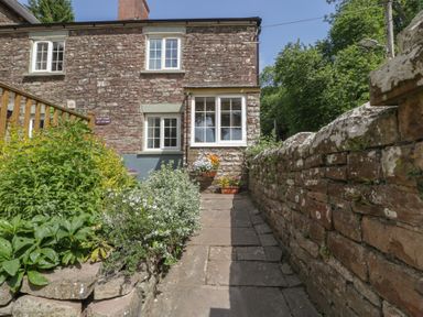 An outdoor path leading to a house with flowers at Court House Cottage in Gatcombe near Blakeney