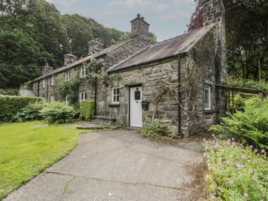 A stone house with a garden and pathway at Glandwr Cottage in Llanbedr