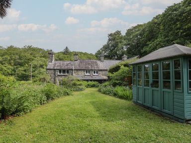 A garden with a house and a shed at Glandwr Cottage in Llanbedr