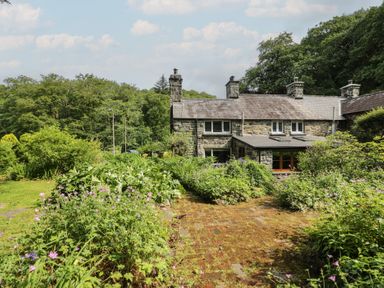 A cottage with a garden and stone pathway at Glandwr Cottage in Llanbedr