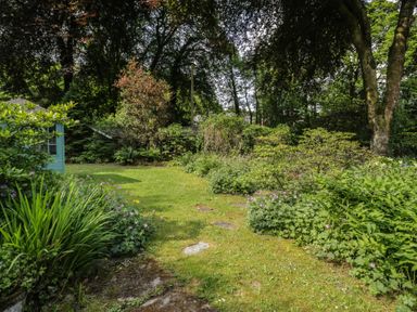 A garden with flowers and trees at Glandwr Cottage in Llanbedr
