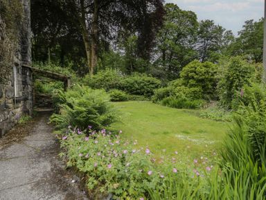 A garden with pathway and flowers at Glandwr Cottage in Llanbedr