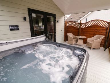 A covered outdoor area with a hot tub and a table with two wicker chairs at Binevanagh Cabin in Magilligan near Castlerock