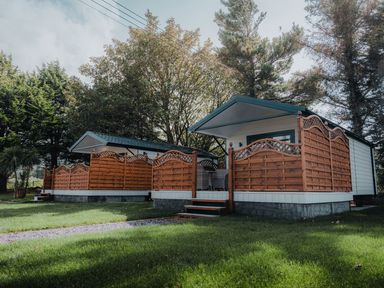 Two small cabins with wooden fences and steps surrounded by grass and trees at Benone Cabin in Magilligan near Castlerock