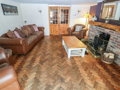 A living room with brown leather sofas a wooden coffee table a brick fireplace and wooden double doors at Greenhaven in Narberth