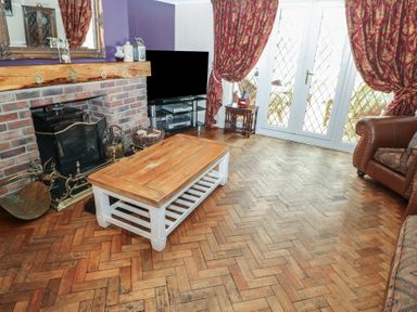 A living room with a wooden coffee table a television and a brick fireplace at Greenhaven in Narberth