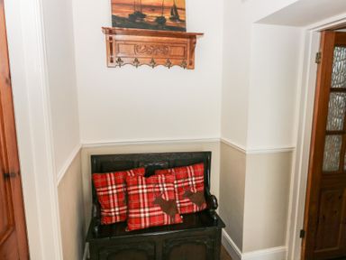 A small wooden bench with three red plaid cushions and a wooden coat rack with hooks above a doorway at Greenhaven in Narberth