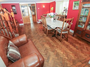 A dining room with wooden chairs a table with a tablecloth flowers and a leather armchair at Greenhaven in Narberth