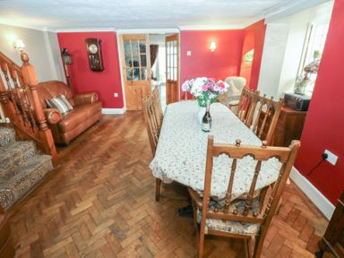A dining room with a wooden table and chairs a sofa and staircase with wooden banisters at Greenhaven in Narberth
