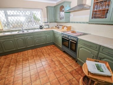 A kitchen with green cabinets a double oven a tiled floor and a large window at Greenhaven in Narberth