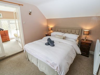 A bedroom with a bed with white bedding and two bedside tables with lamps at Greenhaven in Narberth