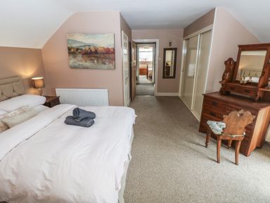 A bedroom with bed folded towels wooden dresser and chair at Greenhaven Narberth