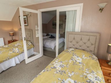 A bedroom with two single beds with floral bedspreads and bedside tables with lamps at Greenhaven in Narberth