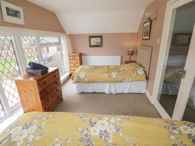 A bedroom with two single beds yellow floral bedspreads wooden dresser and large windows at Greenhaven in Narberth
