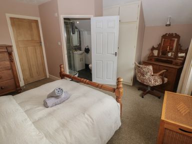 A bedroom with a wooden bed and dresser a floral upholstered chair and an en suite bathroom at Greenhaven Narberth