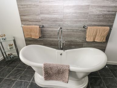 A bathroom with a white freestanding bathtub and beige towels on wall-mounted racks at Greenhaven in Narberth