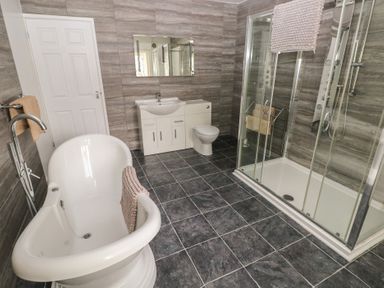 A bathroom with a freestanding bathtub a glass shower enclosure a toilet and a sink cabinet at Greenhaven in Narberth
