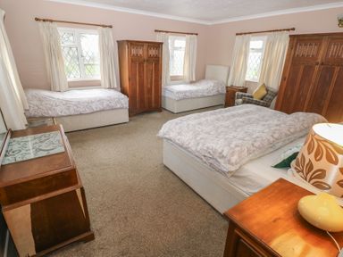 A bedroom with three beds two wooden wardrobes a wooden desk and a chair at Greenhaven in Narberth