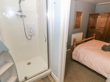 A shower area and a bedroom with a wooden bed frame and wardrobe at Greenhaven in Narberth