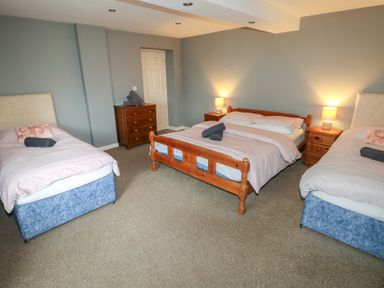 A bedroom with one double bed and two single beds with bedside tables and lamps at Greenhaven in Narberth