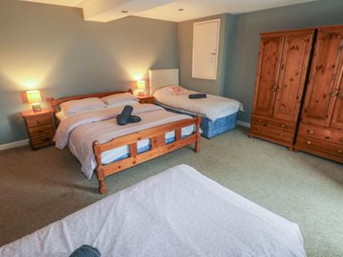 A bedroom with a double bed a single bed two wooden wardrobes and two bedside tables with lamps at Greenhaven in Narberth