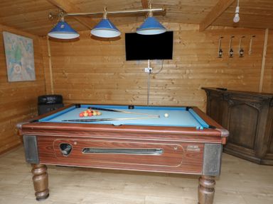A wooden game room with a pool table a wall-mounted television and wooden bar at Greenhaven in Narberth