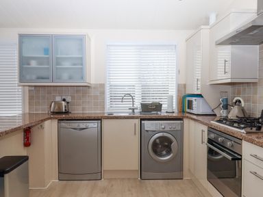 A kitchen with dishwasher washing machine oven stove toaster microwave and sink at Matilda Lodge in Newton Ferrers