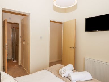 A bedroom with a bed and towels on it two open doors a wall mounted tv and a radiator at Matilda Lodge in Newton Ferrers