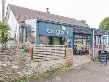 The exterior of a cafe with a sign that says the green and outdoor seating at Matilda Lodge in Newton Ferrers